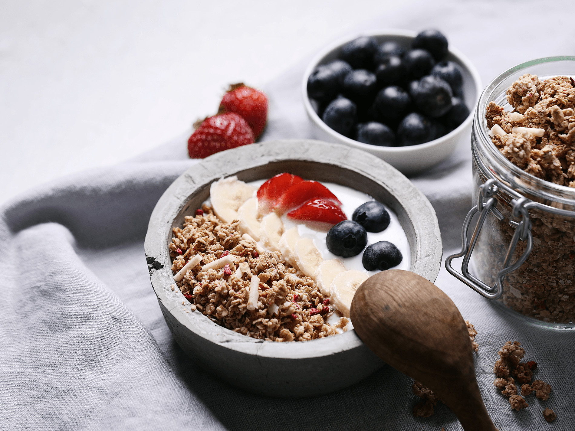 Miska granoli z jagodami, truskawkami i łyżką, idealna na zdrowe śniadanie lub przekąskę.
