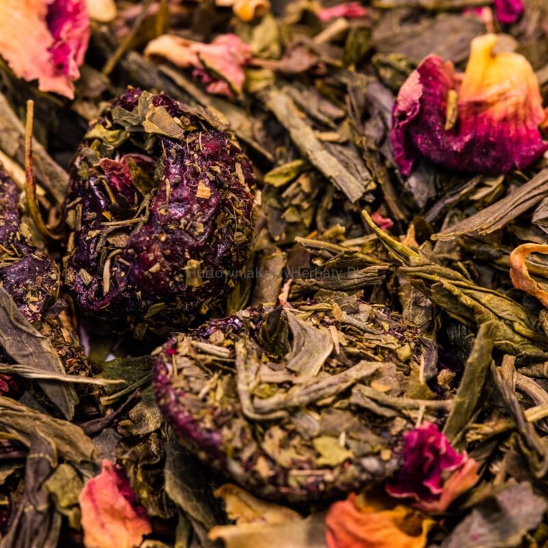 Stos zielonej herbaty z kwiatami i liśćmi, ukazujący naturalne piękno i aromat herbaty.